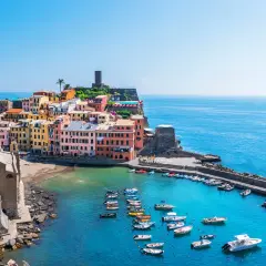 Vue pittoresque des 5 Terres en camping-car : maisons colorées, église, port animé et mer azur.