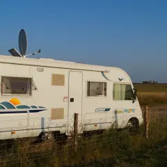 Camping-car blanc stationné dans un champ en Angleterre, avec Stonehenge à l'horizon.