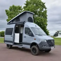 Le plus grand fourgon aménagé, un Mercedes gris avec toit relevable, prêt pour l'aventure.