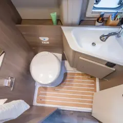 Salle de bain arrière de camping-car : toilette, lavabo et douche intégrée. Pratique pour les voyages.