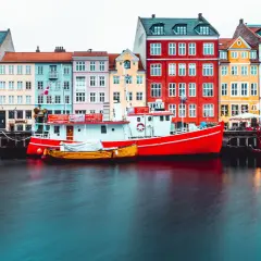 Bateaux rouges et jaunes amarrés devant des maisons colorées, typiques de Copenhague.
