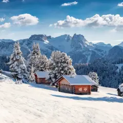 Chalets enneigés sous un ciel bleu, au cœur d'une **caravaneige massif central**. Sapins couverts de neige, montagnes majestueuses en arrière-plan.