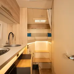 L'intérieur d'un camping-car moderne avec une cuisine fonctionnelle et un coin couchage confortable.