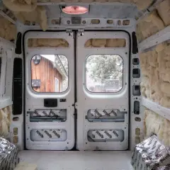 L'isolation d'un camping-car en cours, murs et plafond recouverts de laine de roche et de feuilles d'aluminium.