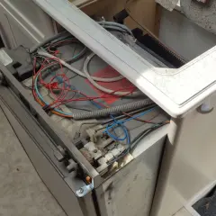 Réparation du frigo camping-car 12v 220v gaz Dometic en panne. Câblage apparent et composants exposés.