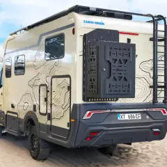 Camping-car Eura Mobil Xtura sur une plage de sable, avec une échelle arrière et un porte-roue noir.