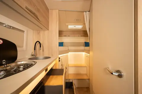 L'intérieur d'un camping-car moderne avec une cuisine fonctionnelle et un coin couchage confortable.