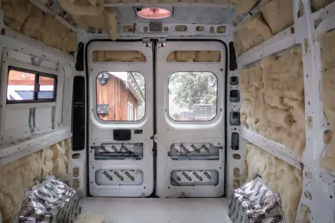 L'isolation d'un camping-car en cours, murs et plafond recouverts de laine de roche et de feuilles d'aluminium.