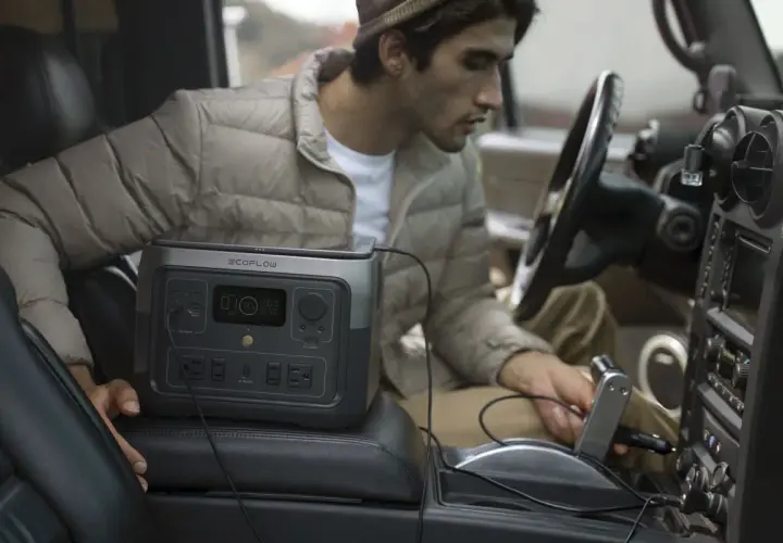 Un homme utilise une station d'énergie EcoFlow River 2 Max dans sa voiture. Avis sur la praticité en déplacement.