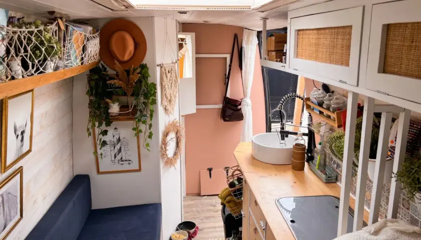 Ambiance chaleureuse et bohème pour ce deco interieur van. Un canapé bleu, des plantes grimpantes, un chapeau tendance et une cuisine fonctionnelle.