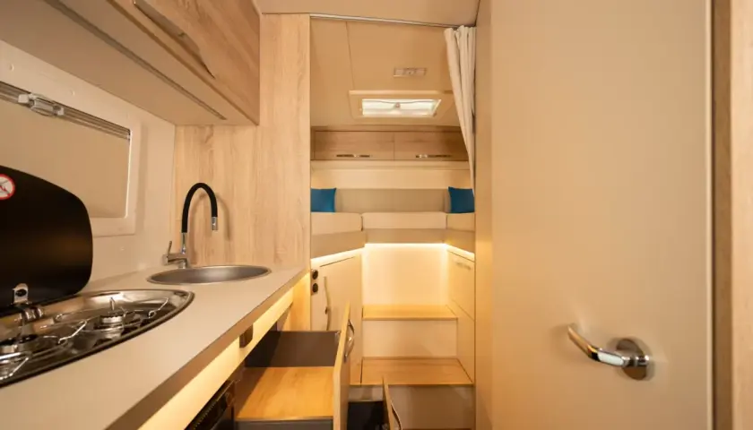 L'intérieur d'un camping-car moderne avec une cuisine fonctionnelle et un coin couchage confortable.