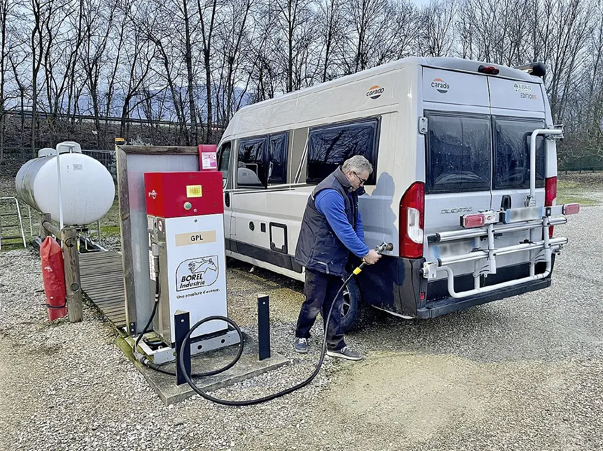 Un homme fait le plein de son camping-car à une pompe GPL. Le bon gaz pour camping car est le GPL.