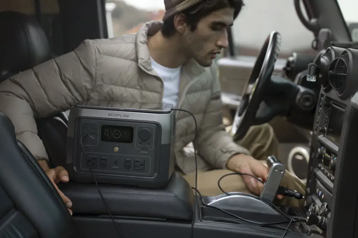 Un homme utilise une station d'énergie EcoFlow River 2 Max dans sa voiture. Avis sur la praticité en déplacement.