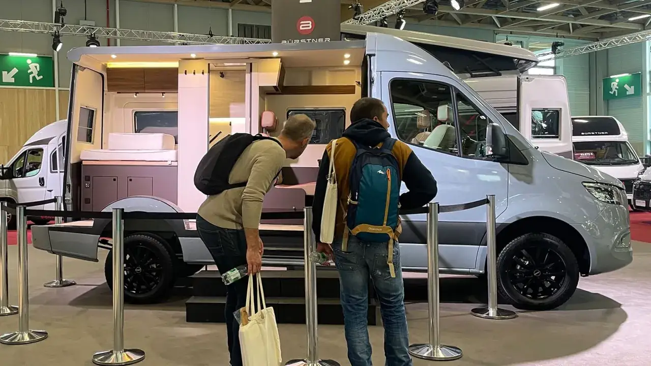 Deux hommes examinent un fourgon am&eacute;nag&eacute; de la marque B&uuml;rstner, un mod&egrave;le de camping-car moderne et spacieux.