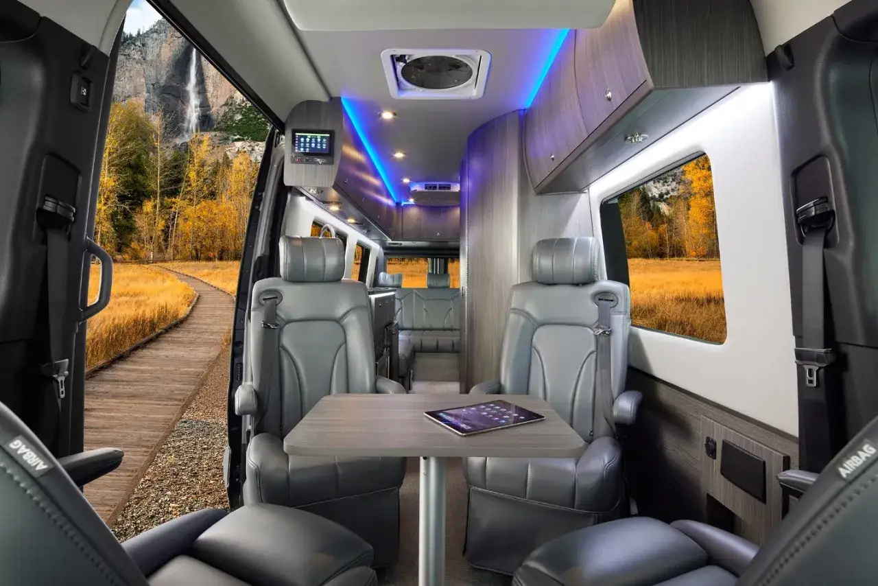Int&eacute;rieur luxueux d'un camping-car Pilote, avec si&egrave;ges en cuir, &eacute;clairage d'ambiance et vue sur une cascade.