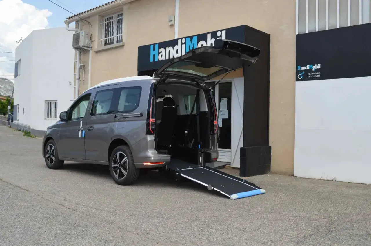 Un fourgon aménagé PMR avec rampe d'accès déployée, prêt à faciliter le transport.
