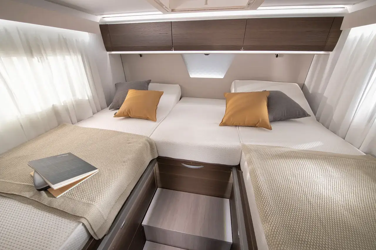 Lits jumeaux confortables dans un camping-car Adria Matrix 670 SC, avec coussins et rangements pratiques.