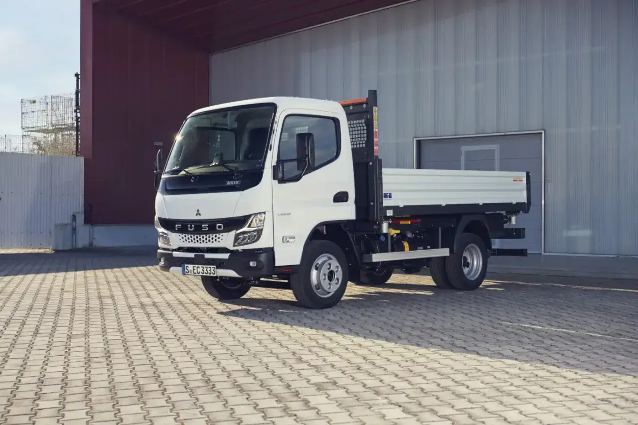 Un Fuso Canter 4x4 blanc, prêt à affronter tous les terrains, stationné devant un bâtiment industriel.