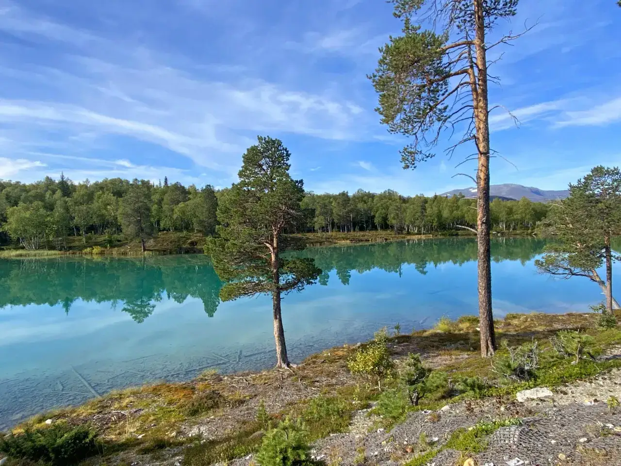 Magnifique lac aux eaux turquoise, refl&eacute;tant une for&ecirc;t dense sous un ciel bleu. Un endroit parfait pour un s&eacute;jour en camping-car.