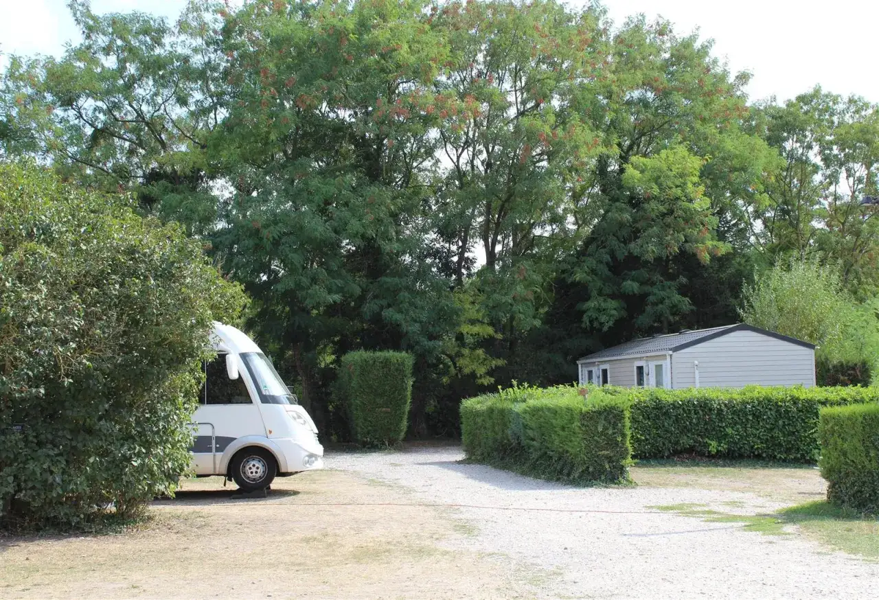 Un camping-car blanc est gar&eacute; pr&egrave;s d'une petite maisonnette, entour&eacute; de verdure. Id&eacute;al pour un s&eacute;jour au Parc Ast&eacute;rix.