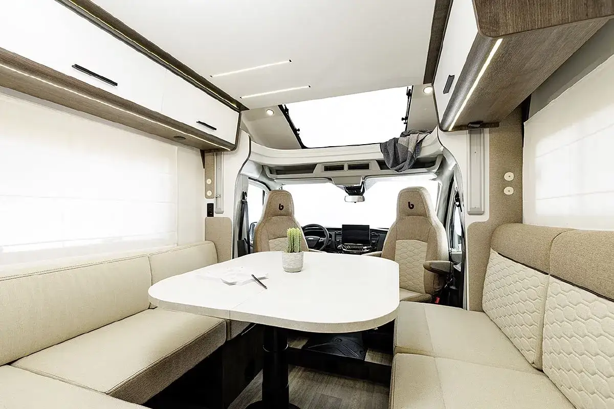 Intérieur d'un camping-car moderne, avec banquettes confortables, table et sièges pivotants. Ces innovations transports camping car offrent un espace de vie lumineux et fonctionnel.