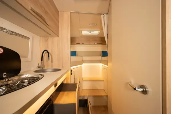 L'intérieur d'un camping-car moderne avec une cuisine fonctionnelle et un coin couchage confortable.