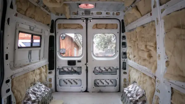 L'isolation d'un camping-car en cours, murs et plafond recouverts de laine de roche et de feuilles d'aluminium.